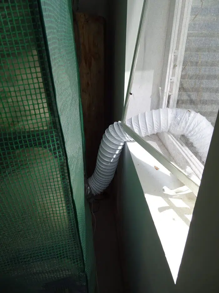 4-inch (10cm) flexible ducting exiting the lower left-hand corner of the greenhouse and piping spores and air to the outside.