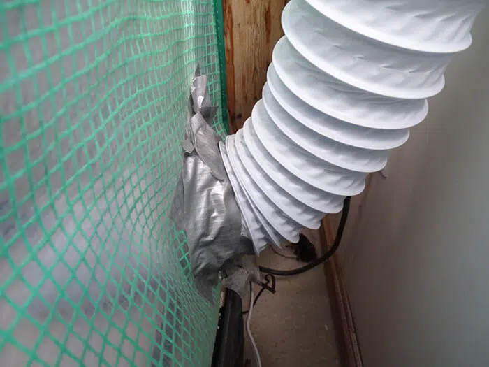 4-inch (10cm) flexible ducting exiting the greenhouse in the lower left-hand corner. The duct tape is there to seal the hole and connect another length of ducting to the fan, which then pushes air and spores outside. 